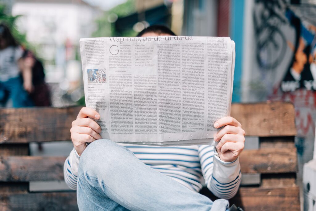 Person sitting on steps reading a newspaper