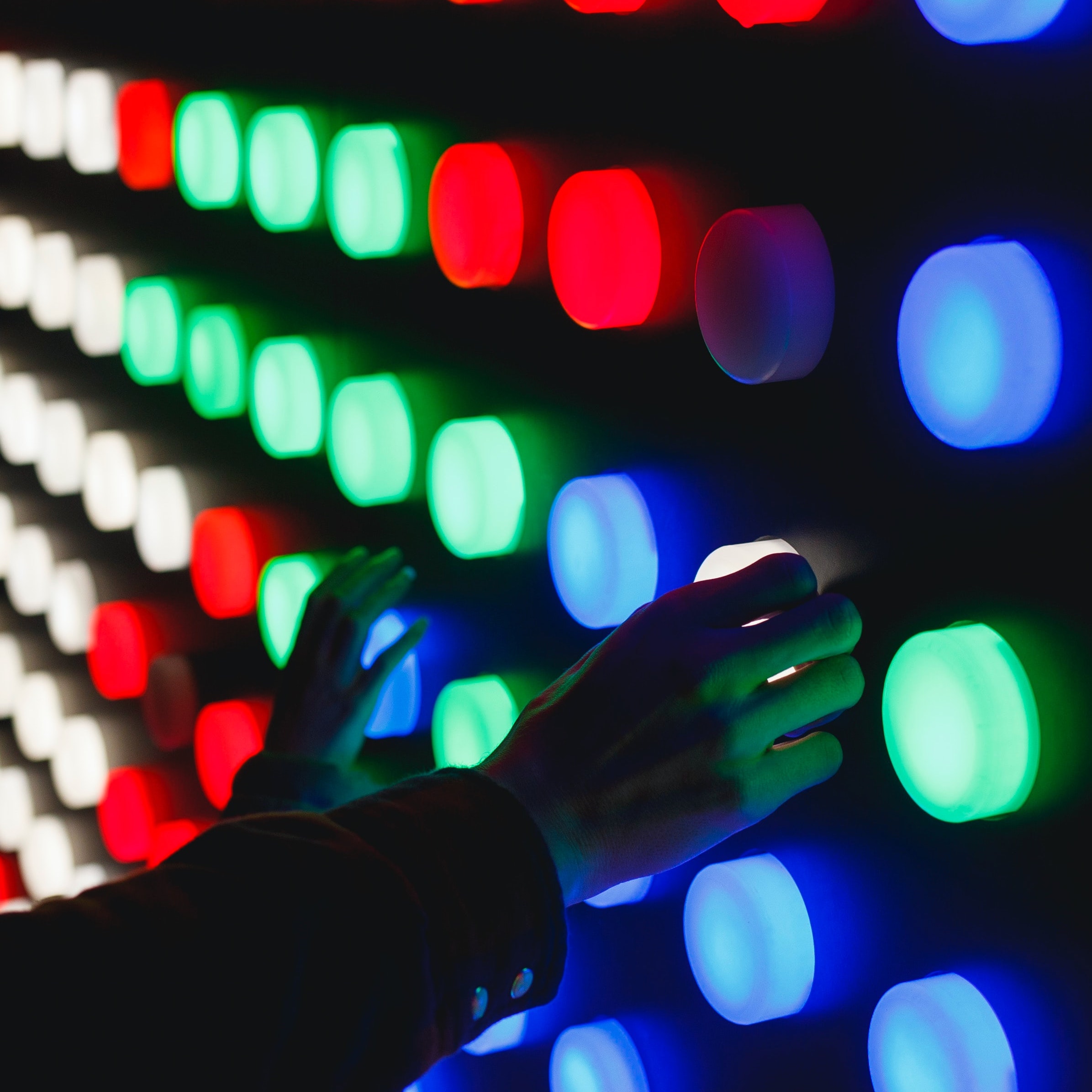 Hands touching circular board of lights