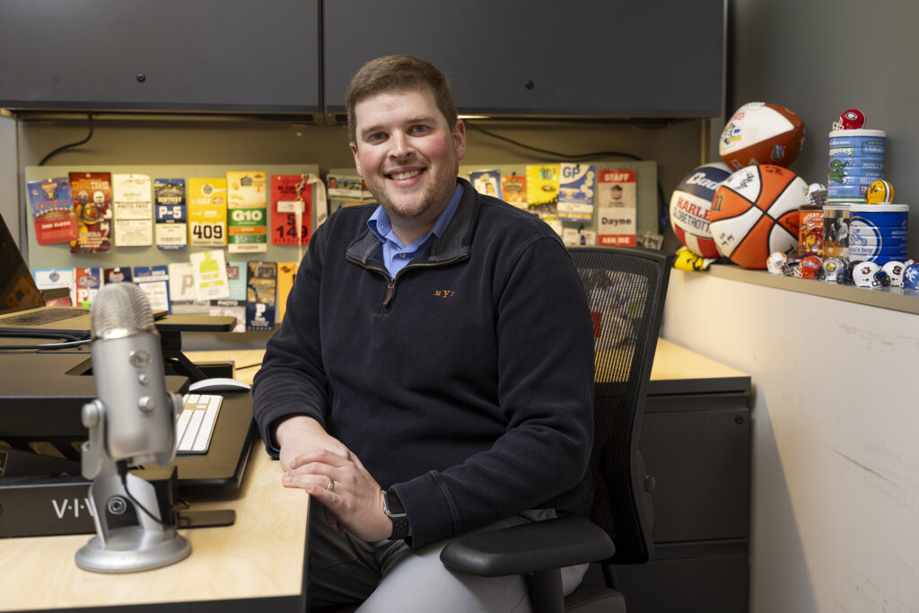 A portrait of program coordinator Dayne Young of the New Media Institute and Carmical Sports Media Institute among his sports media memorabilia in his office at the Journalism Building.